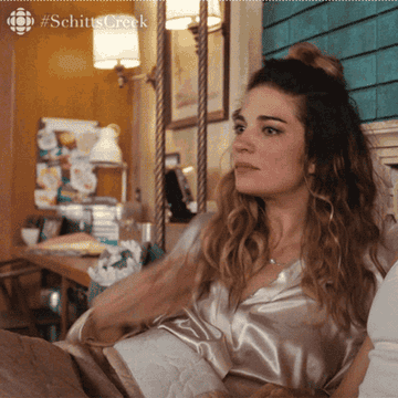 Gif of Alexis from Schitt's Creek sweating in bed