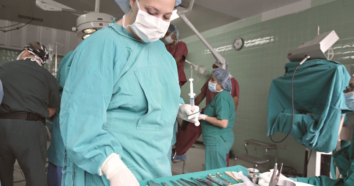 Surgeons and nurses in an operating room preparing for surgery with medical tools.
