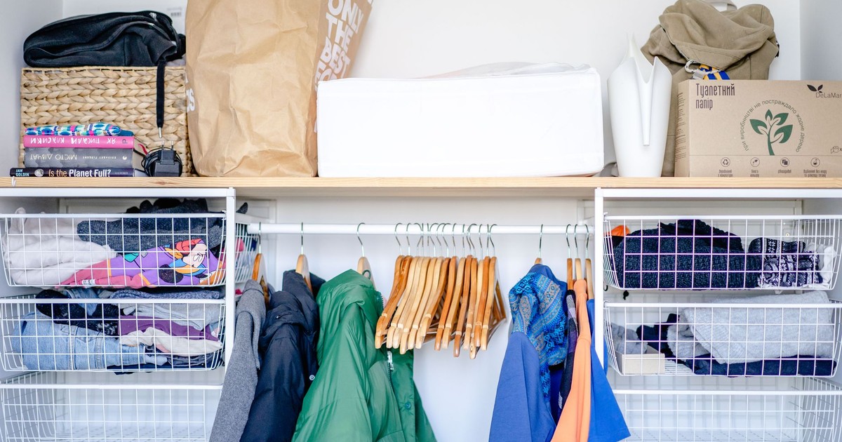 A minimalist open wardrobe featuring modern clothing, hangers, and storage baskets.