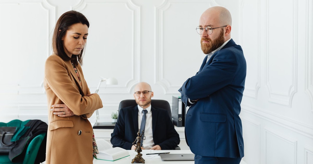 A couple in corporate attire seeks mediation during a business disagreement in an office setting.