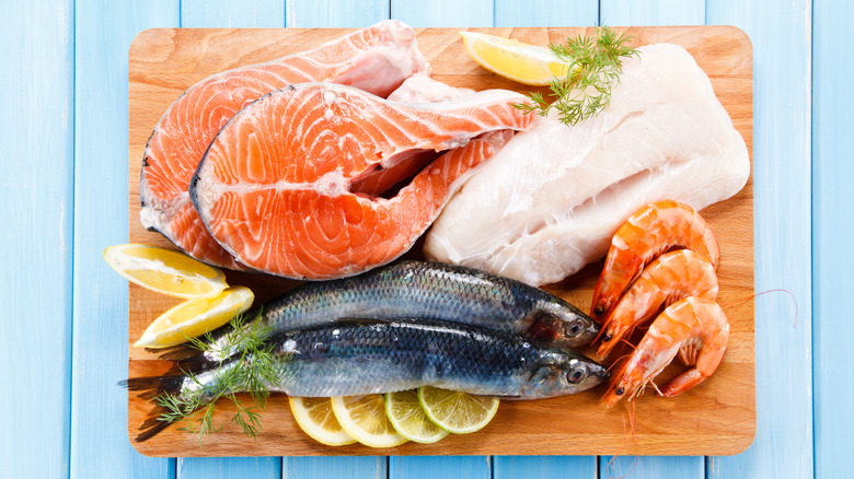 Salmon and cod on a cutting board with shrimp and other fish