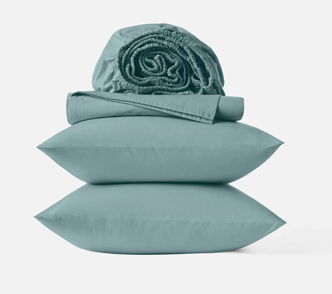 Folded bed sheets and two pillows neatly stacked, showcasing a complete bedding set