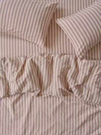 Striped bed linens with two pillows and a ruffled cover, showcasing a cozy and inviting bedroom look