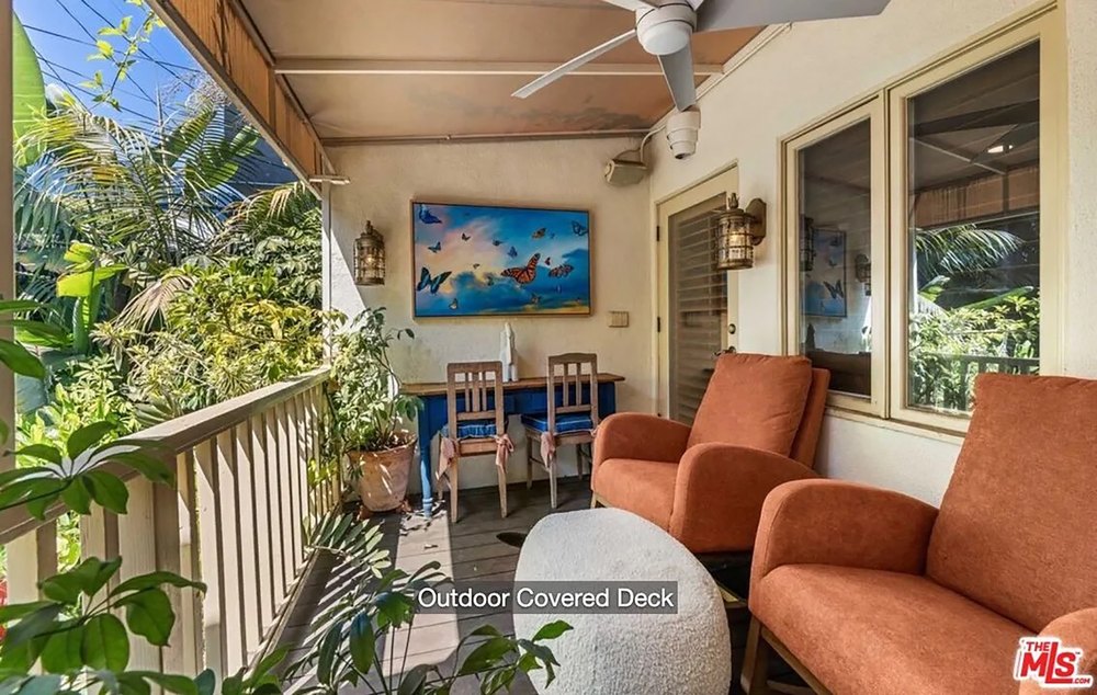 Cozy outdoor covered deck with bright orange armchairs and a table set.
