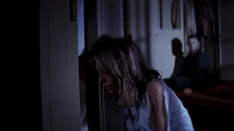 Laurie Strode (Jamie Lee Curtis) weeps while Michael Myers (Nick Castle) sits up behind her in Halloween (1978)