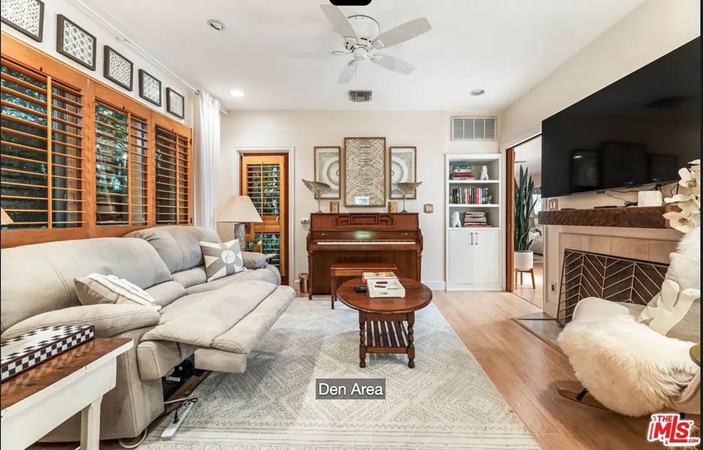 Cozy den area featuring a classic piano, neutral-toned sofa, and fireplace.