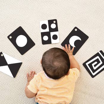 Baby on carpet, playing with high-contrast black-and-white flashcards designed for visual stimulation and early learning