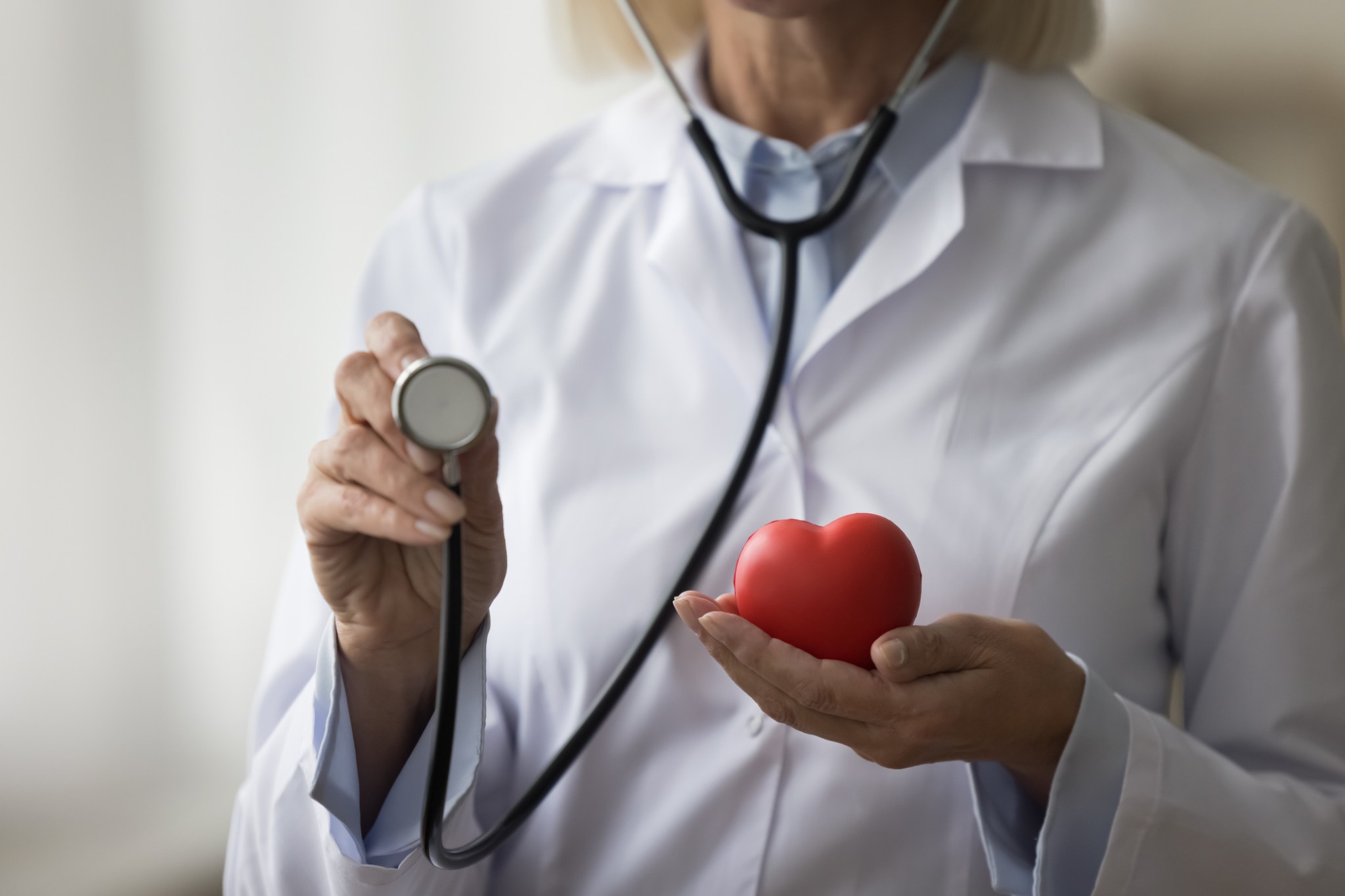 Unknown female doctor holding in hands heart and stethoscope tool