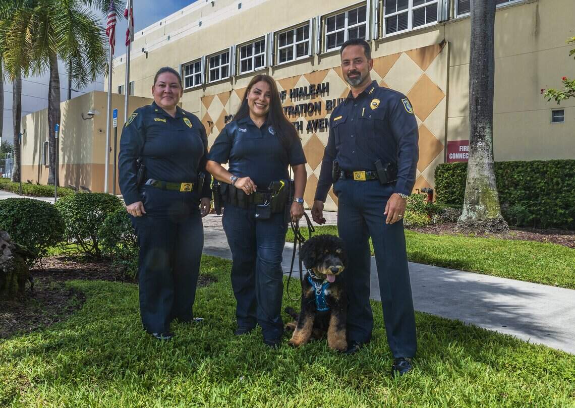 Hialeah Police Department Commander Patricia Salgado, far left, and Chief of Police George Fuente, flank Officer Lucicarmen Lopez and Domino, the official Hialeah Police Therapy Dog at police headquarters on June 16, 2026.