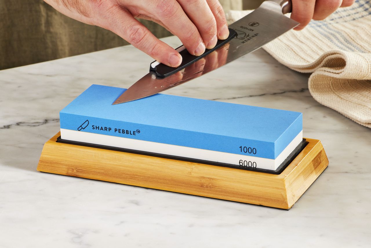 A person sharpening a knife on the Sharp Pebble Premium Knife Sharpening Stone