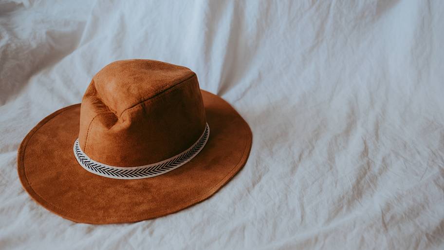 Cowboy hat on a white bed.