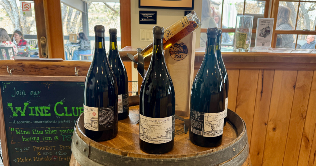 a display of wine bottles on top of a wine barrel at page springs cellars in cornville arizona