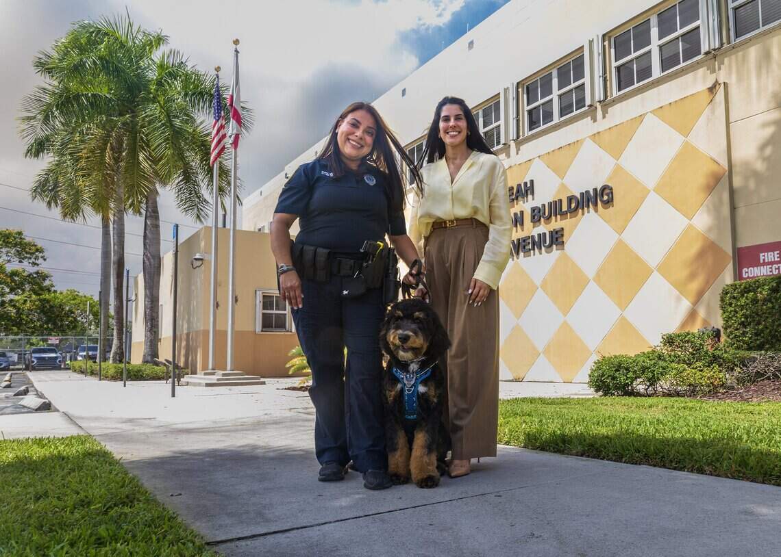 Hialeah Council member Gelien Perez poses with officer Lucicarmen Lopez and Domino, the official Hialeah Police Therapy Dog, at police headquarters on June 16, 2026.