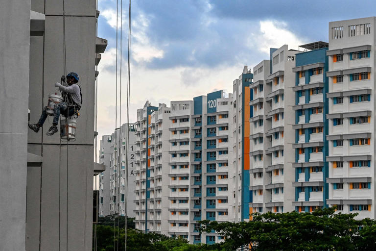 A worker paints an apartment building in Singapore last month. Housing is among the costs the city state wants to make more manageable for prospective parents. Photo: AFP