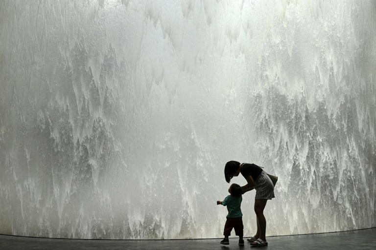 A mother and her child stand next to the Rain Vortex display at Singapore's Jewel Changi Airport. Photo: AFP