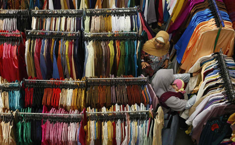 A woman carrying her baby shops at a Hari Raya bazaar in Singapore. Photo: Reuters