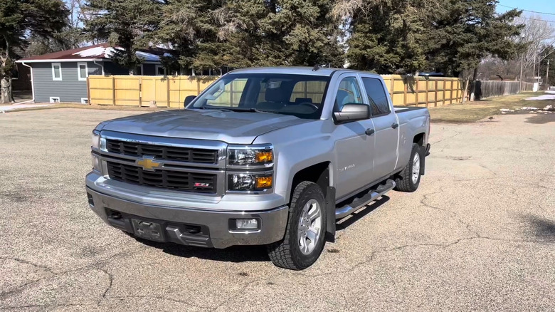 A silver 2014 Chevrolet Silverado parked on a cracked road.