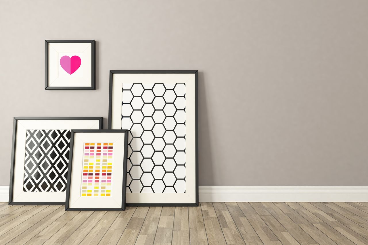 Framed abstract artworks leaning against a wall on a wooden floor