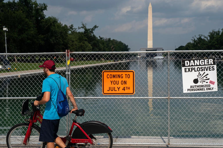 A man on a bike passes security fencing along the edge of the Lincoln Memorial Reflecting Pool ahead of America 250 July 4th celebration on the National Mall, Thursday, July 2, 2026, in Washington. (AP Photo/Nathan Howard)
