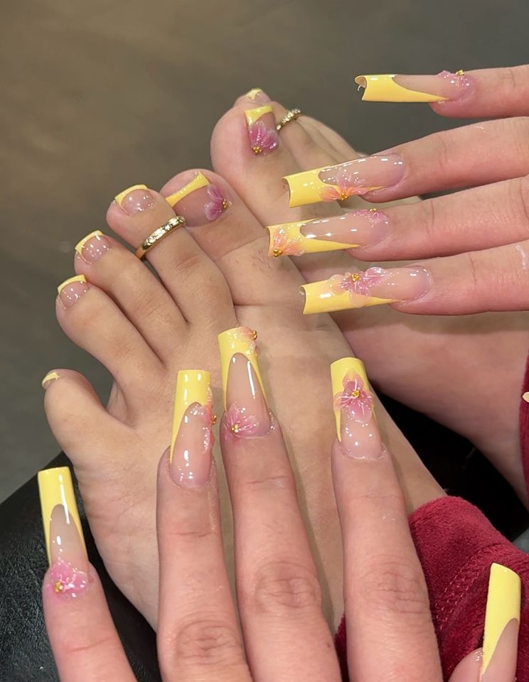 Closeup of manicured hands and pedicured feet with yellow and decorated nails