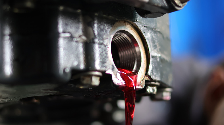 Close-up of transmission fluid pouring out of drain plug