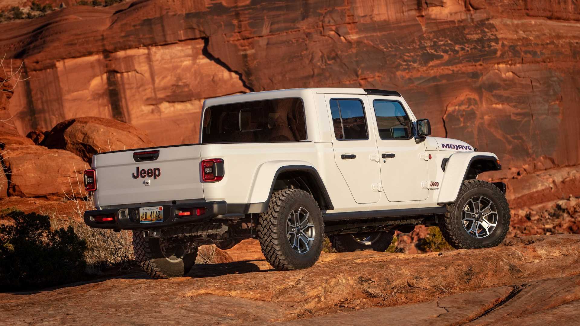 The bed of a white 2026 Jeep Gladiator parked in the desert.