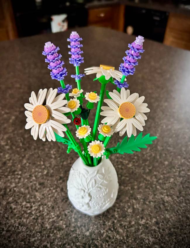 LEGO flower bouquet with daisies and lavender in a decorative white vase on a countertop