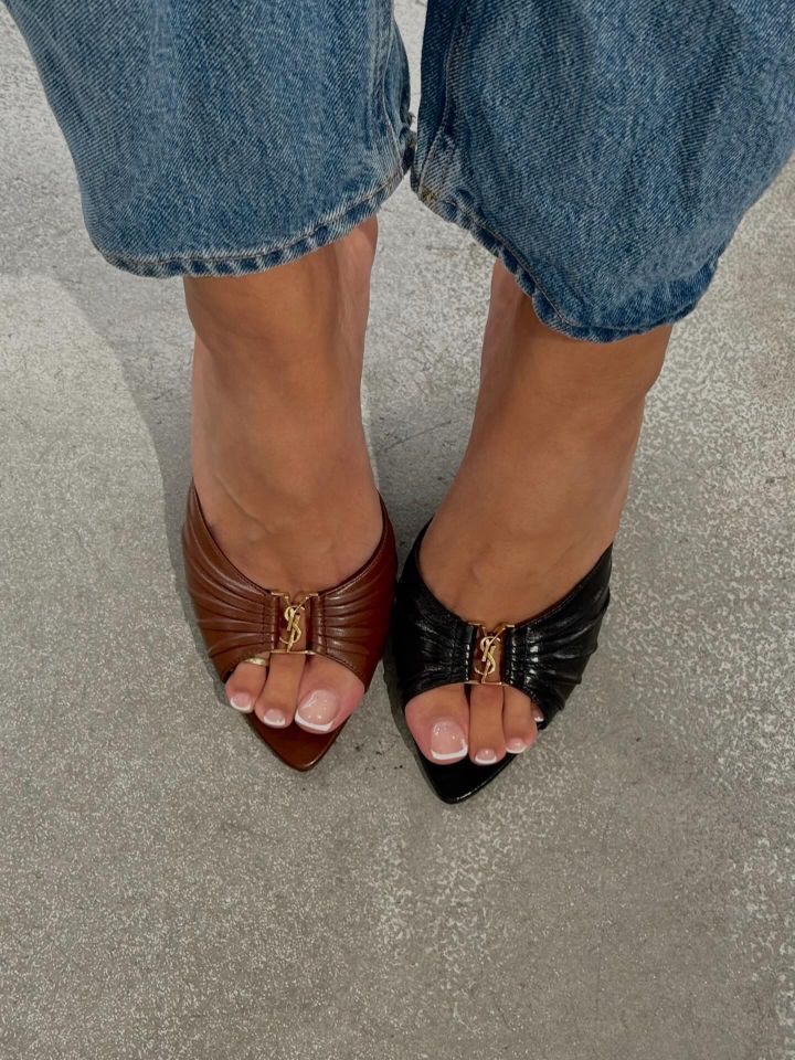 A person wearing mismatched pointedtoe shoes one brown and one black with the same design