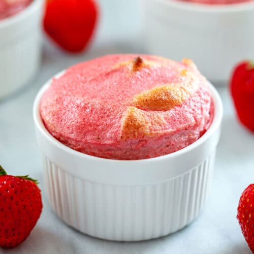 Head-on view of strawberry souffle in white ramekin with strawberries all around