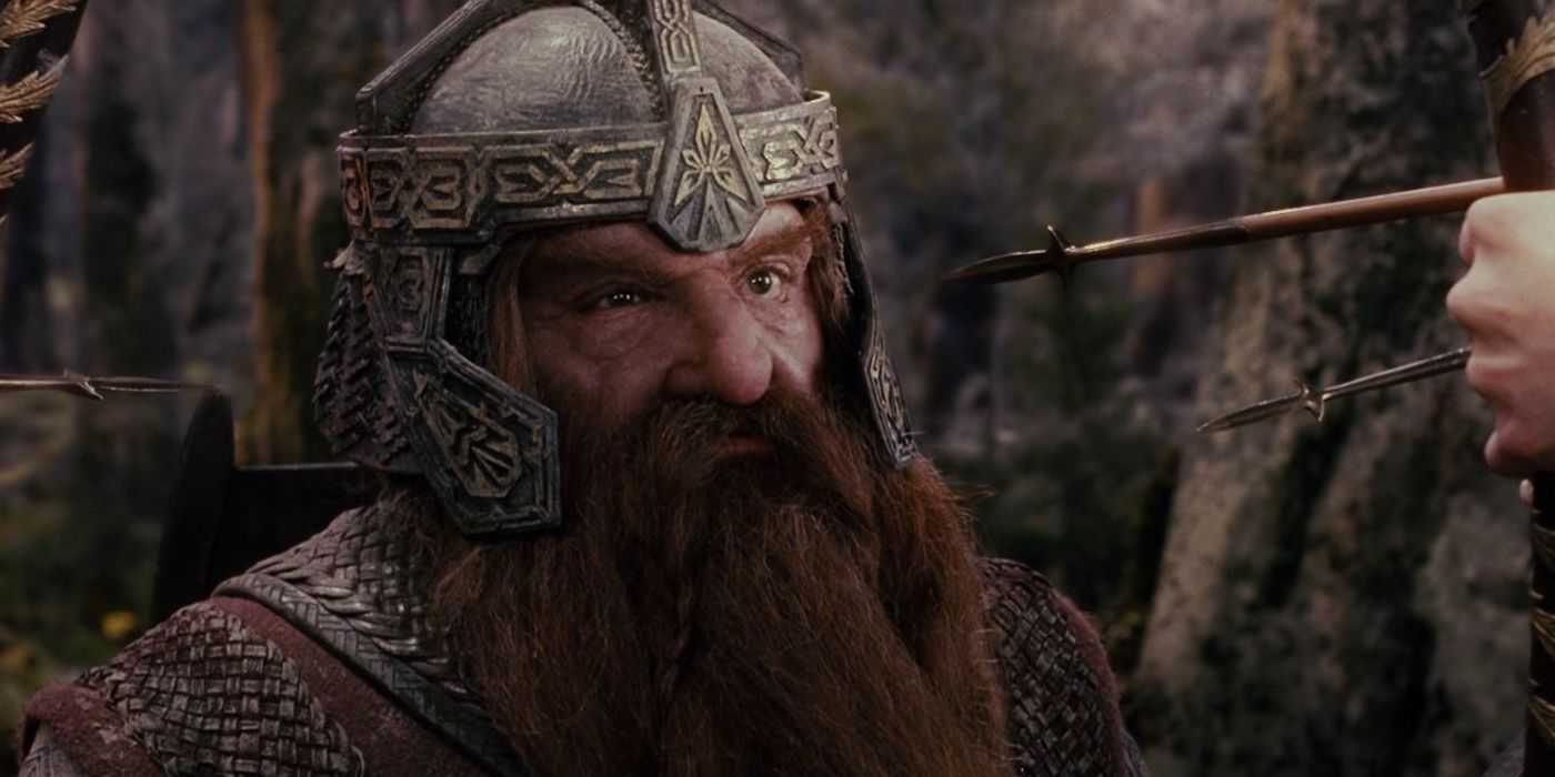 Gimli looks stern facing arrows in The Lord of the Rings wearing a helmet.