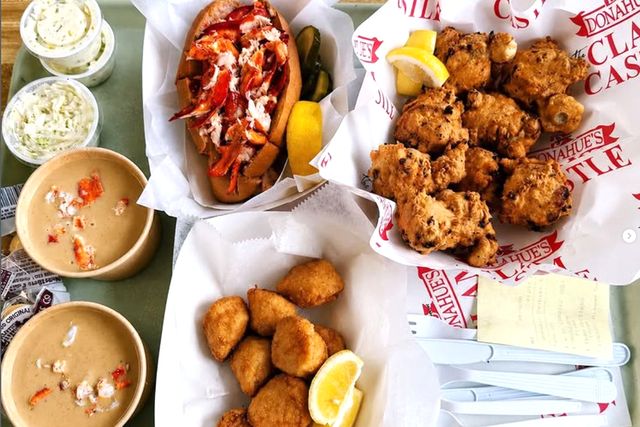 A seafood meal featuring lobster rolls clam chowder and fried seafood items on a table at Donahue's Clam Castle.