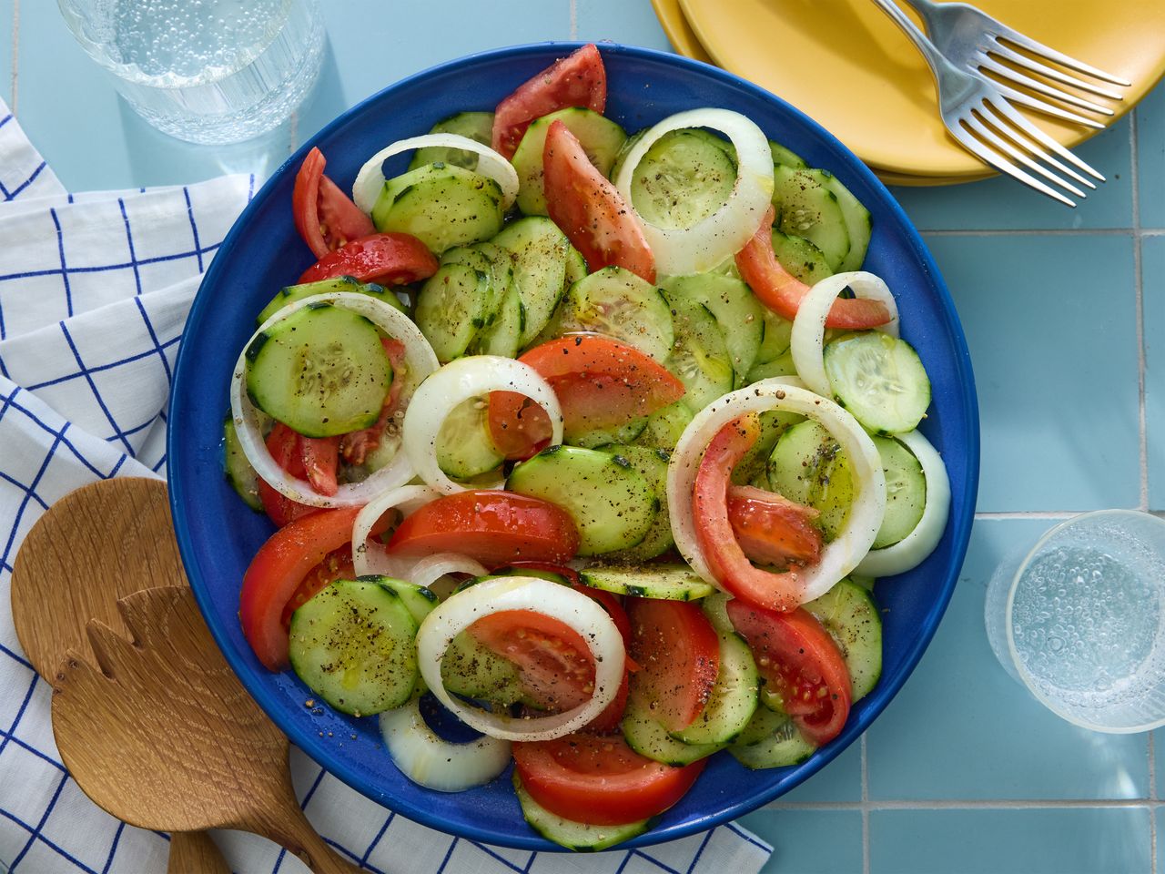 Marinated cucumber, onion, and tomato salad served in a blue bowl.