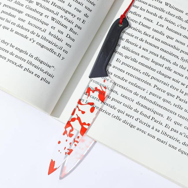 Knife bookmark with red splotches placed in open book, lying flat