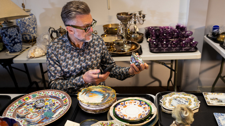 A man examines antique pottery pieces with intricate patterns