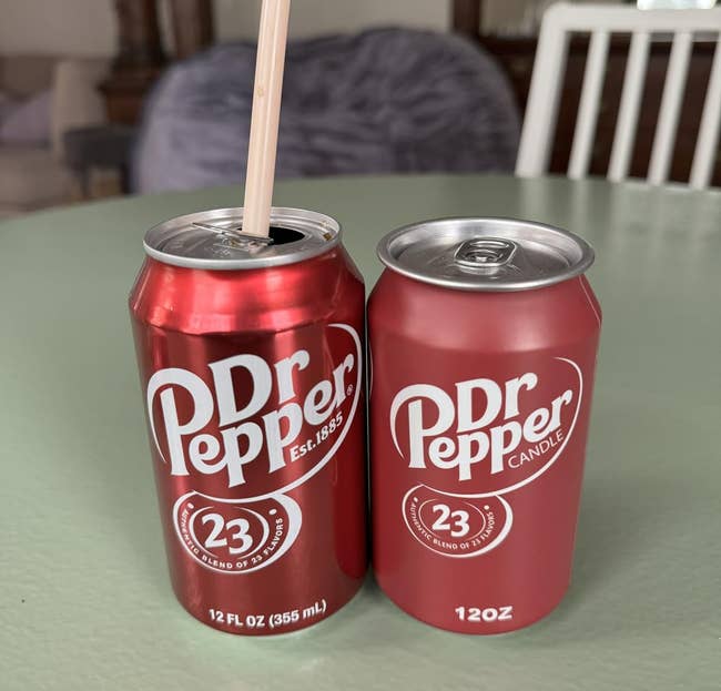 Two red Dr Pepper cans, one with a straw. The second can is labeled as a candle, suggesting novelty home décor
