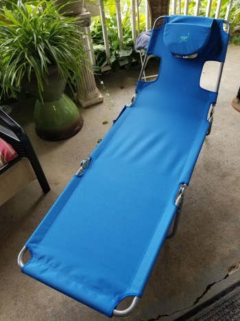The blue chaise lounge in reviewer's backyard with the pillow covering the face hole