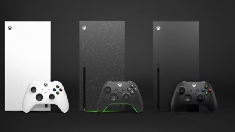 Three Xbox Series X and their controllers stand lined up together