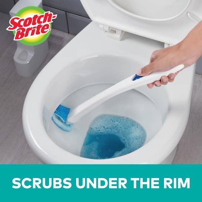 Person using a Scotch-Brite toilet scrubber to clean under the toilet rim