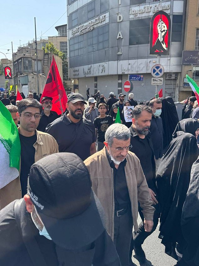 Iran's former president Mahmoud Ahmadinejad, who was reported dead at the start of the war, has been spotted at the funeral of his country's Supreme Leader. He is pictured in this image wearing a light brown jacket and a mask pulled down to his neck