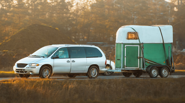 Green horse trailer being towed by white minivan