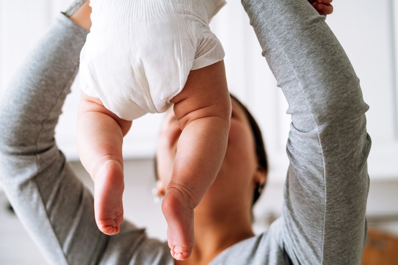 A young mother holds her baby in the air
