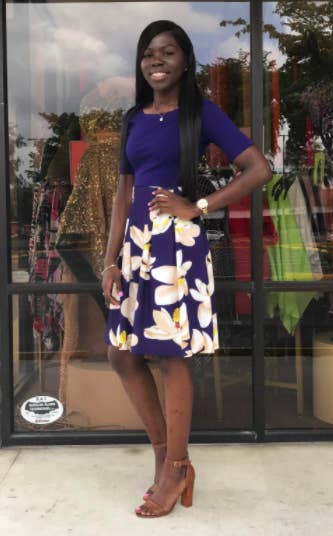 A reviewer wearing the short-sleeve dress with a blue bodice and blue and white floral pleated skirt