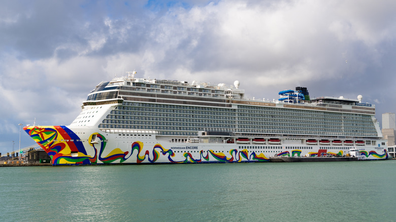 A Norwegian Cruise Line ship docked in a harbor with a cloudy sky
