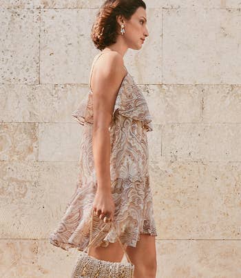 model wearing ruffle bust spaghetti strap white and brown dress strutting down street
