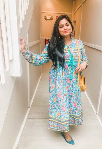 reviewer in the long sleeve aqua, yellow, and pink print maxi dress with tassel detail