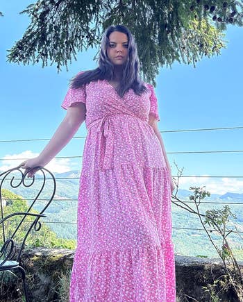 reviewer in pink short sleeve tiered dress with small floral print and belt and vneck