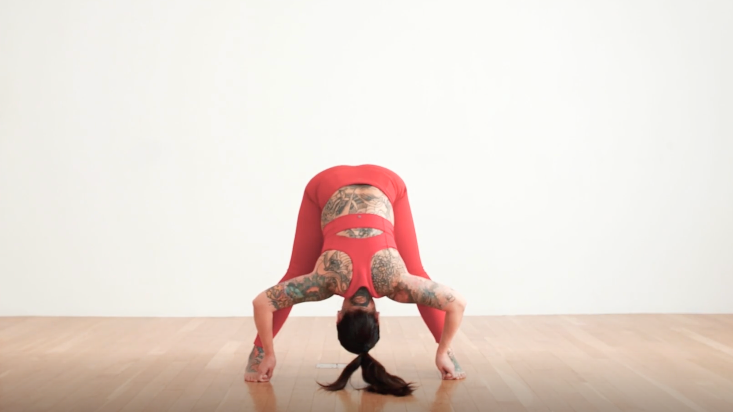 A woman in Standing Wide-Legged Forward Bend, a yoga pose for stress