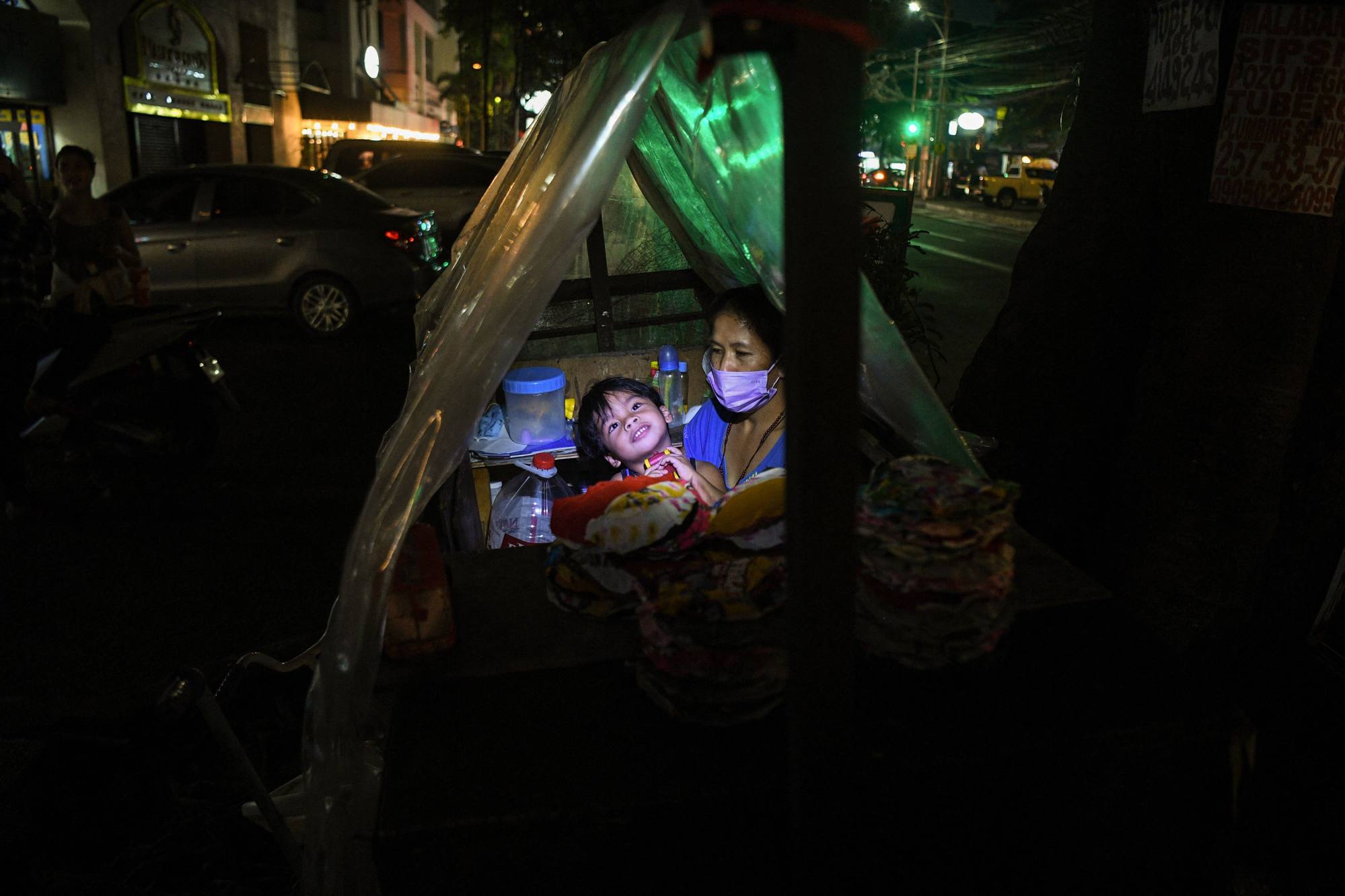 A woman and her son rest inside their pushcart