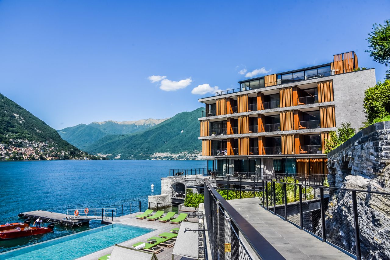 A contemporary resort by a lake with mountains in the background featuring a pool and dock