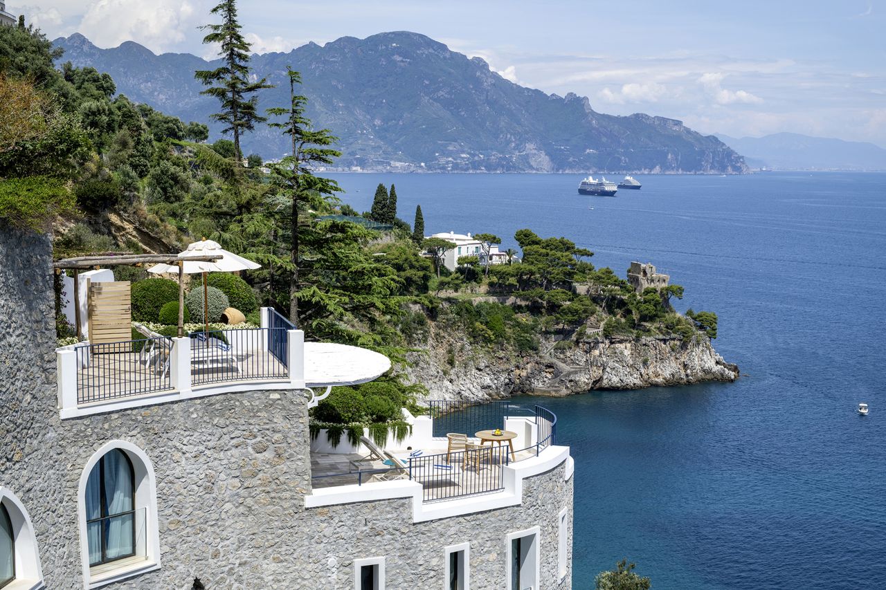 Mediterranean coastline with villa terraces overlooking the sea and distant mountains balconies and outdoor seating visible